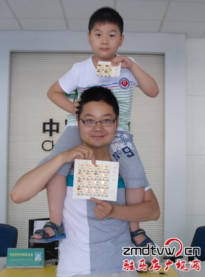 圖為6月13日，一對父子在市中心郵政所展示“感恩父親”特種郵票 .JPG