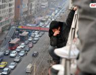 圖為2014年1月3日，蘭州，6名農(nóng)民工為了討薪爬上白銀路一居民樓9樓平臺要“跳樓”。原來，該樓4層的甘肅天安建筑機械工程公司拖欠24名工人的24萬元工錢，他們討要5個月毫無結(jié)果，便做出危險之舉。后經(jīng)有關(guān)部門多方協(xié)調(diào)，工人們當(dāng)場拿到了18萬元。于永昭/視覺中國