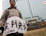 2006年1月24日，在京從事降水井工程的老陳掛著寫有“賣判決書”的紙口袋在北京站口附近來回走著。曾是名小工頭的老陳被欠工程款4萬元，為了給工人們開資不得已賣掉了打井機器。2002年法院宣判老陳勝訴，可四年后該判決仍得不到執(zhí)行，無奈之中老陳只好上演此幕。程寧/視覺中國