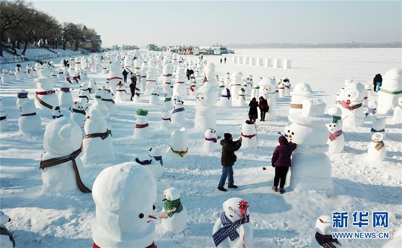 1月2日，市民、游客在雪人群中游玩觀賞（無人機(jī)拍攝）。2019個(gè)各式各樣的雪人，近日在冰城哈爾濱市的松花江畔亮相，引來眾多市民游客游玩觀賞。新華社記者 王建威 攝